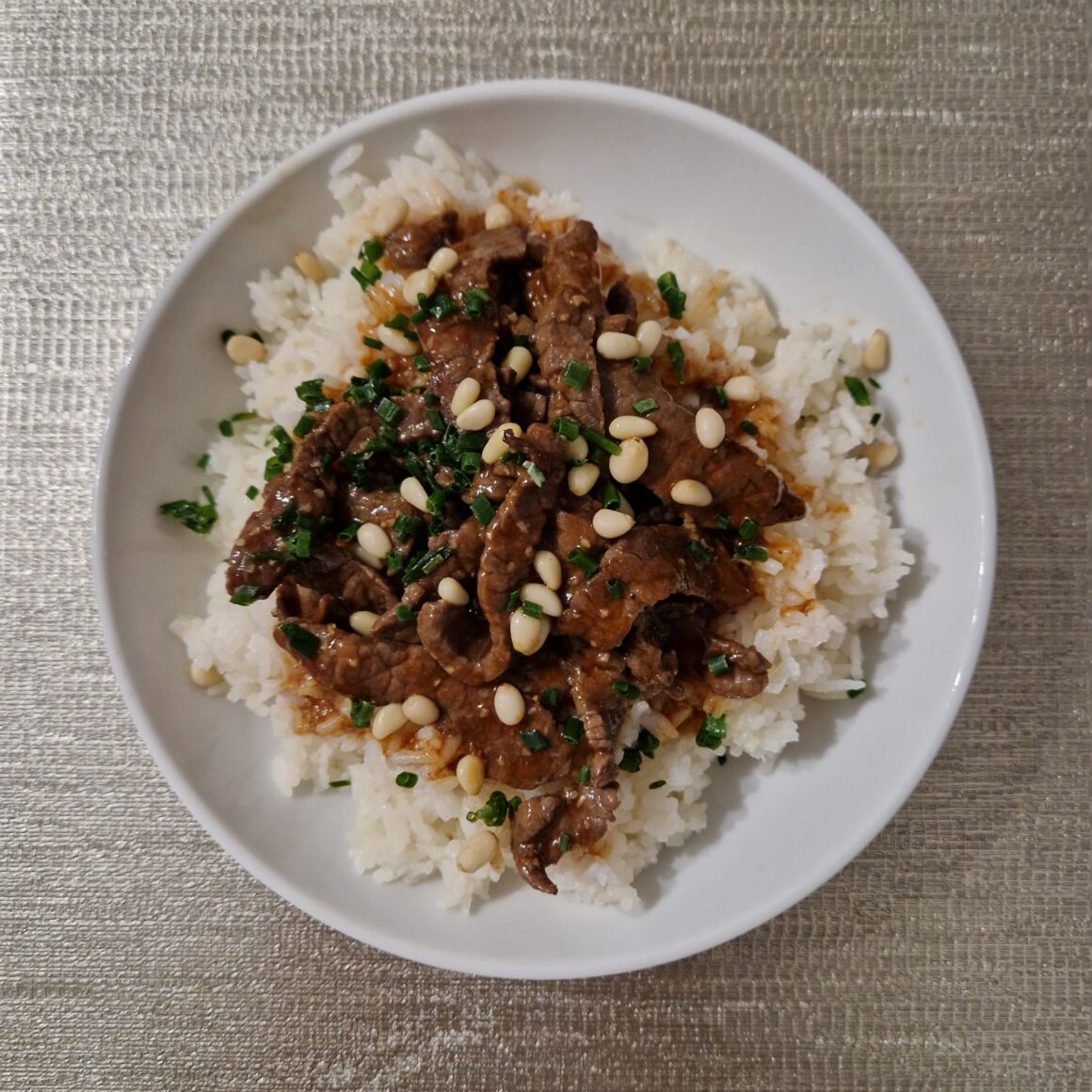 Assiette de riz blanc avec bœuf sauté, pignons de pin et sauce brillante, vue de dessus