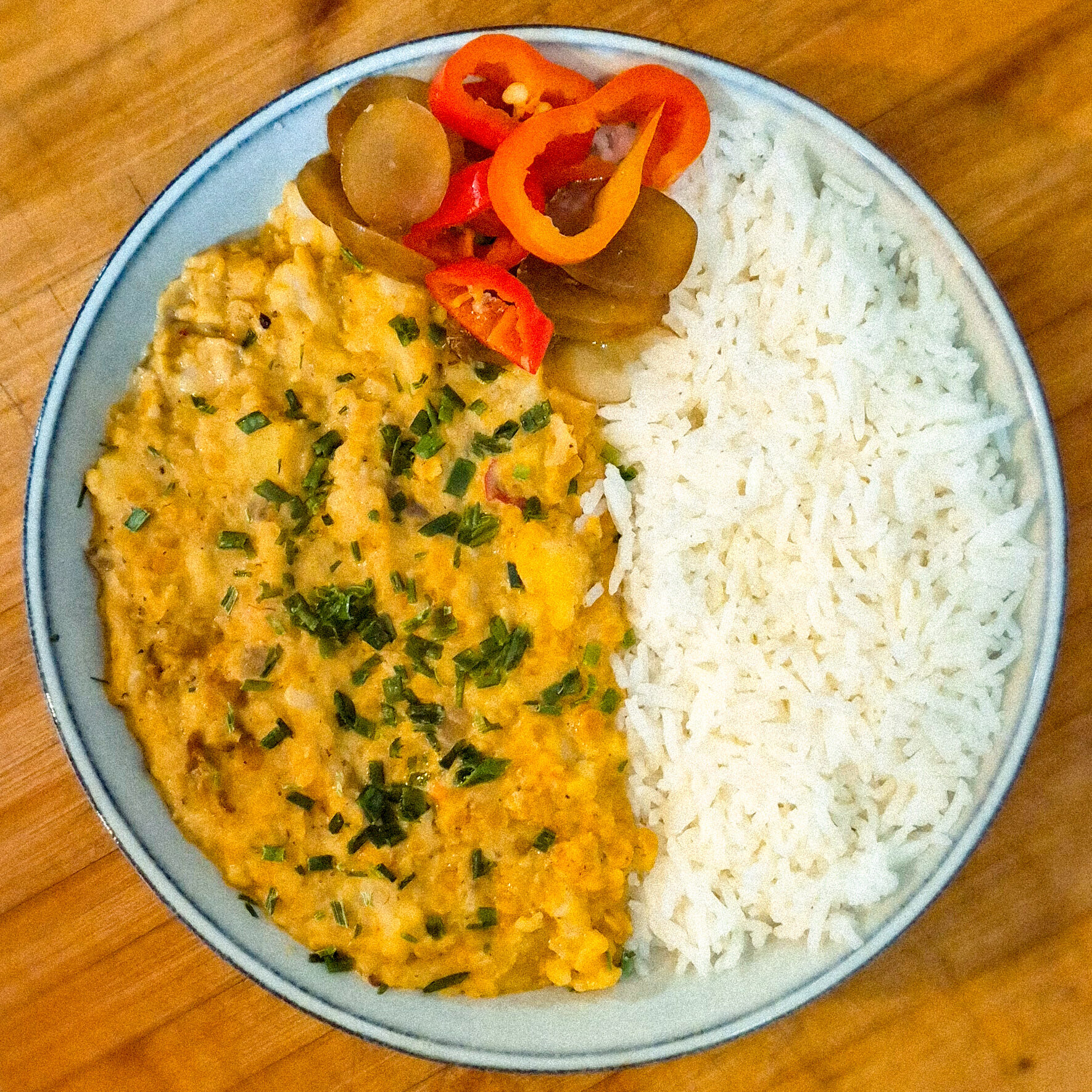 Bol de riz blanc servi avec un dhal de lentilles onctueux, herbes fraîches et légumes marinés
